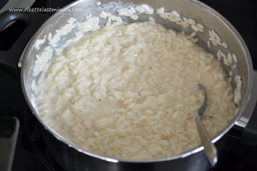 Pentola con riso in cottura con acqua e latte leggermente zuccherato