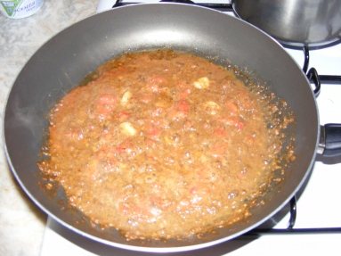 Polpa di riccio, pomodori, olio e aglio che cuociono in padella