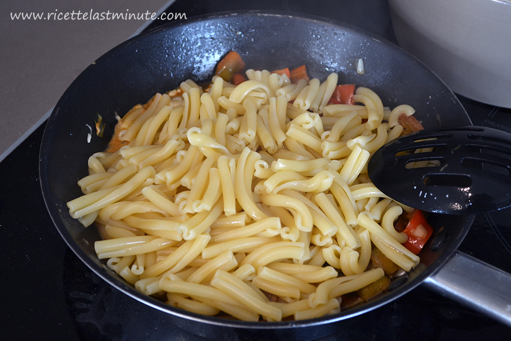 Aggiunta della pasta al condimento di peperoni, cipollina e formaggio